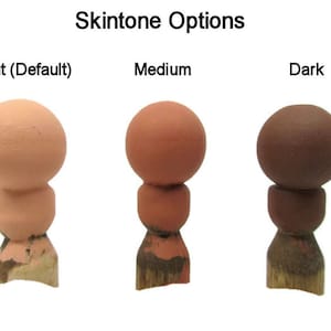 May include: Three wooden doll heads painted in different skin tones: light, medium, and dark. The heads are on wooden bases.