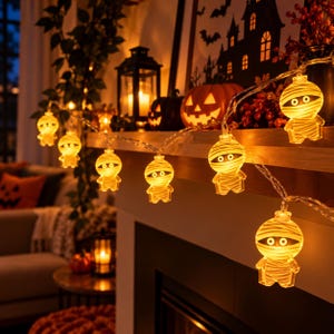May include: A string of LED fairy lights featuring translucent, glowing mummy-shaped covers. Each mummy figure has a wrapped texture and two visible eyes, emitting a warm yellow light. The lights are connected by a clear, flexible wire.
