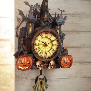 May include: A wall clock shaped like a dark, multi-towered castle with bats, two glowing orange jack-o'-lanterns, and two small skulls. The clock face features Roman numerals and a warm yellow light. A ghost-shaped pendulum hangs from the bottom.