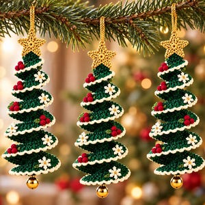 Puede incluir: Tres adornos de árbol de Navidad tejidos a ganchillo en verde oscuro con bordes festoneados blancos, racimos de bayas rojas y detalles de copos de nieve blancos. Cada árbol tiene una estrella dorada tejida y una pequeña campana dorada.