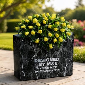 Puede incluir: Una lápida rectangular de mármol negro con vetas blancas, coronada con un gran arreglo de rosas amarillas y follaje verde. El frente presenta el texto en blanco DESIGNED BY M&E y This Stone is 61 cm for Reference Only.