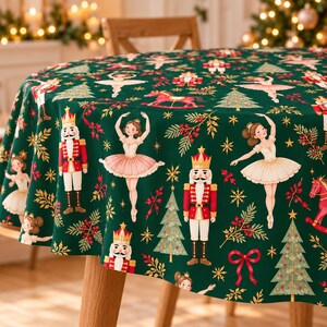 May include: A round tablecloth in dark green featuring a repeating pattern of nutcrackers in red uniforms, ballerinas in white and pink tutus, rocking horses, Christmas trees, gold stars, red berries, and red bows.