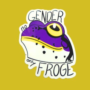 May include: A die-cut sticker featuring a stylized purple and white frog with a large yellow eye. The text GENDER no only FROGE is written in black ink around the frog. The design uses a white border against a solid mustard yellow background.