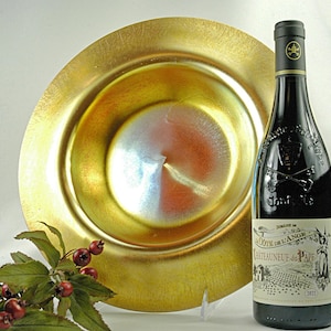 May include: A gold iridescent glass bowl with a wide rim and a wine bottle with a black label that says "La Cote de L'Ange Chateau neuf du Pape 2013".