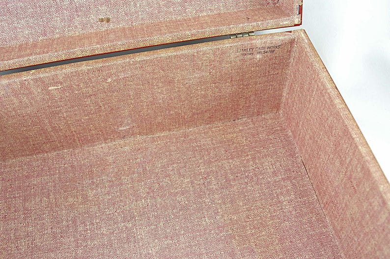 May include: Open vintage box with a red fabric interior. The box is lined with a textured, reddish-pink material. The lid is open, revealing the inside of the box. The text "Stanley Case Works" is visible.