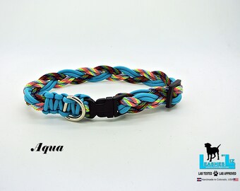 Puede incluir: Collar para perro trenzado aqua con una hebilla de plástico negra y un anillo en D plateado. El collar está hecho de paracord y tiene un patrón de arcoíris.