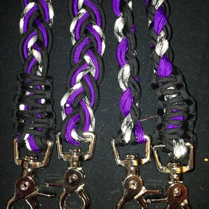 May include: Four braided paracord leashes with silver swivel clips. The leashes are black, white, and purple.