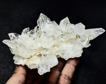 May include: A cluster of clear, translucent quartz crystals with sharp, pointed terminations and multifaceted surfaces. The mineral formation features a bright, icy white appearance with visible internal fractures and natural geometric structures.
