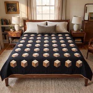 May include: A black quilt featuring a repeating pattern of three-dimensional cubes in shades of tan, beige, and brown. The quilt is draped over a wooden bed frame with white pillows and a rectangular gray accent pillow placed at the head of the bed.