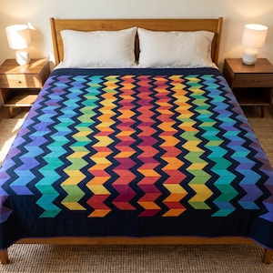 May include: A bed quilt featuring a vibrant rainbow chevron pattern set against a deep navy blue background. The design consists of vertical zig-zag stripes in shades of purple, blue, green, yellow, orange, and red, creating a bold geometric effect.