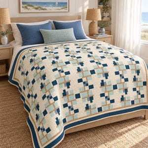 Op de afbeelding: Een bedsprei met een geometrisch patroon van verticale strepen in marineblauw, lichtblauw en beige op een gebroken witte achtergrond. De sprei heeft een effen marineblauwe rand en ligt over een bed met twee marineblauwe kussens.