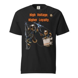 May include: A black short-sleeve t-shirt featuring a graphic of two German Shepherd dogs dressed as utility workers repairing power lines. The text "High Voltage. Higher Loyalty." is printed in orange above the dogs, with a small paw print logo.