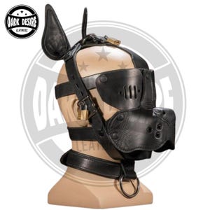 Peut inclure: Une cagoule en cuir noir de style animal avec des oreilles droites, une section nasale en forme de museau avec des trous d'aération et des œillères à fentes verticales. L'accessoire comprend des sangles réglables et deux cadenas en laiton.