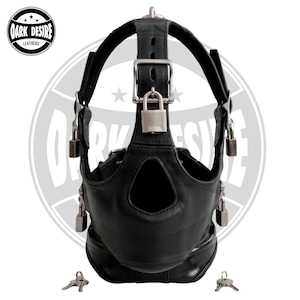 May include: A black leather head harness featuring a central nose opening, multiple adjustable straps with silver-toned metal buckles, and four silver padlocks attached to the sides and top. Two small metal keys are positioned at the bottom.