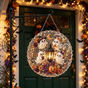May include: A circular hanging sign featuring four white ghosts, a central black lantern, a crescent moon, stars, and a pumpkin. The design is decorated with purple and orange flowers and small beads. It hangs from a black metal shepherd's hook.