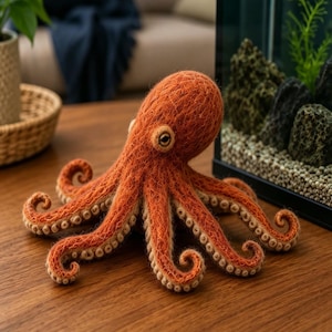 May include: A needle-felted orange octopus plush toy with a textured, fibrous surface. The octopus features a rounded head, eight curled tentacles, and small, light-colored circular suckers lining the underside of each arm. It has dark eyes.