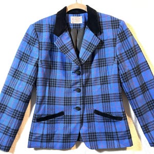 May include: A blue blazer featuring a black plaid pattern with thin red lines. The jacket has a black velvet collar and matching black velvet trim on the two front pockets. It includes three black fabric-covered buttons and a Pendleton brand label.