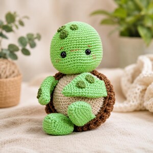 May include: A crochet turtle toy featuring a light green head with dark green spots, black eyes, and pink blush marks. The body has a beige belly, light green limbs with dark green spots, and a dark brown textured shell on the back.