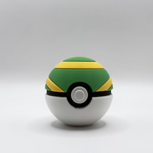 Op de afbeelding: Een bolvormig object met een witte onderste helft en een bovenste helft met afwisselende groene en gele horizontale banden. Een zwarte cirkelvormige band omcirkelt het midden, met een kleine witte knop in het midden van de voorzijde.