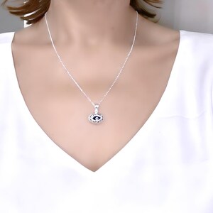May include: A silver chain necklace with a small, silver eye pendant. The eye is black with a white pupil and is surrounded by a silver frame.