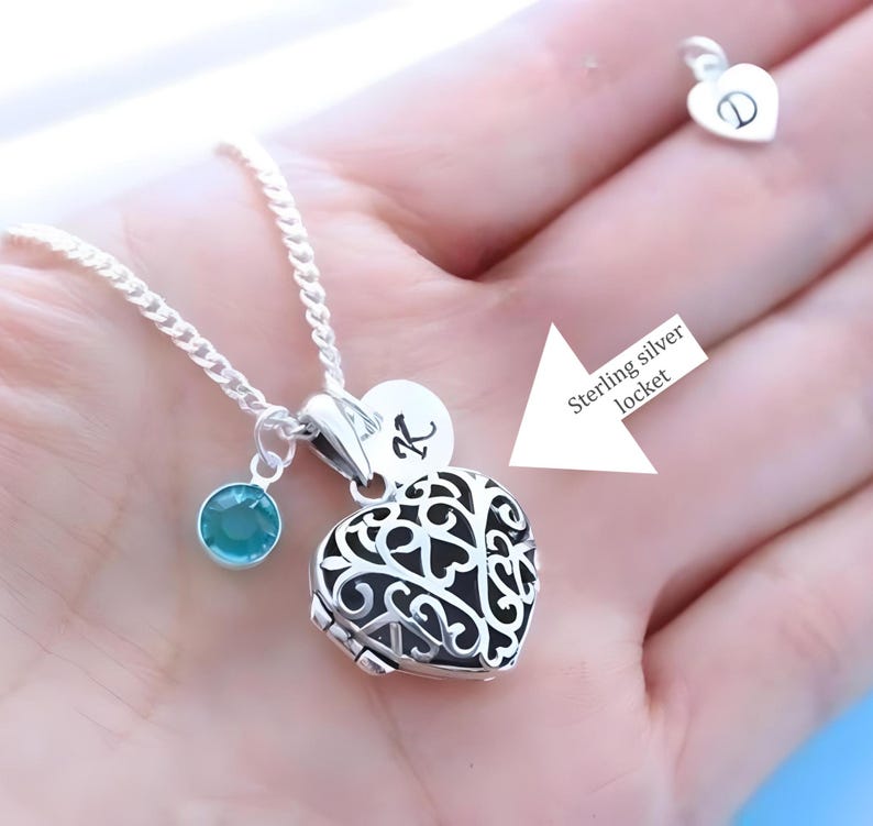 Puede incluir: Un collar de plata con un dije en forma de coraz&oacute;n con un delicado dise&ntilde;o de filigrana. El dije tiene un peque&ntilde;o dije de piedra turquesa y un dije redondo con la letra "K" grabada. El collar est&aacute; en una cadena de plata.