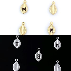 May include: Assortment of gold and silver leaf charms with different letters and numbers engraved on them. The charms are perfect for adding a personalized touch to jewelry projects.