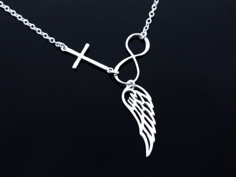 May include: Silver necklace featuring a cross, infinity symbol, and a single wing pendant.