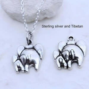 May include: A silver-toned necklace featuring a pendant shaped like two elephants, accompanied by a separate matching elephant charm. The text "Sterling silver and Tibetan" is visible. The pendant hangs from a delicate silver-toned chain.