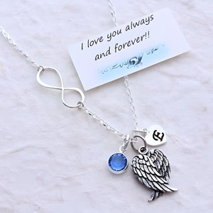 May include: Silver necklace with an infinity symbol, a small heart charm with the letter E, a blue crystal, and angel wings. The necklace comes with a card that reads "I love you always and forever!"
