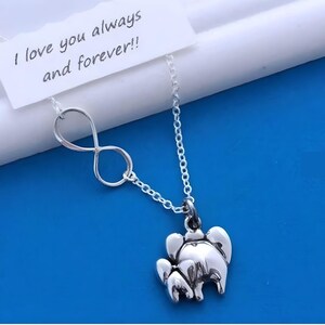 May include: A silver-toned necklace featuring an infinity symbol charm and a small elephant-shaped pendant. A white rectangular card is attached to the chain, displaying the printed black text: I love you always and forever!!