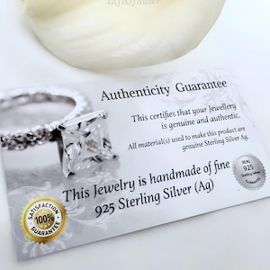 Puede incluir: Una tarjeta blanca con el texto "Authenticity Guarantee" y "This certifies that your Jewellery is genuine and authentic. All material(s) used to make this product are genuine Sterling Silver Ag. This Jewelry is handmade of fine 925 Sterling Silver (Ag)" impreso en ella. La tarjeta tambi&eacute;n tiene un peque&ntilde;o c&iacute;rculo plateado con el texto "REAL 925 Sterling Silver GUARANTEE" impreso en &eacute;l.