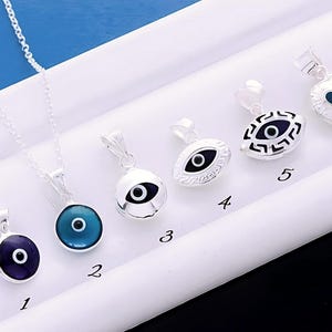 May include: A set of ten silver necklaces with blue evil eye pendants. The pendants are in different shapes and sizes, including round, oval, and heart-shaped. The necklaces are numbered 1 through 10.