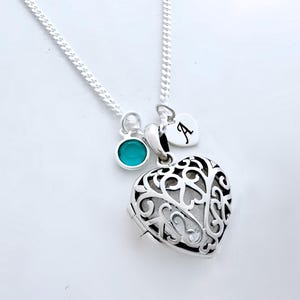Puede incluir: Un collar de plata con un dije en forma de coraz&oacute;n, un dije turquesa y un peque&ntilde;o dije en forma de coraz&oacute;n con la letra 'A' grabada.