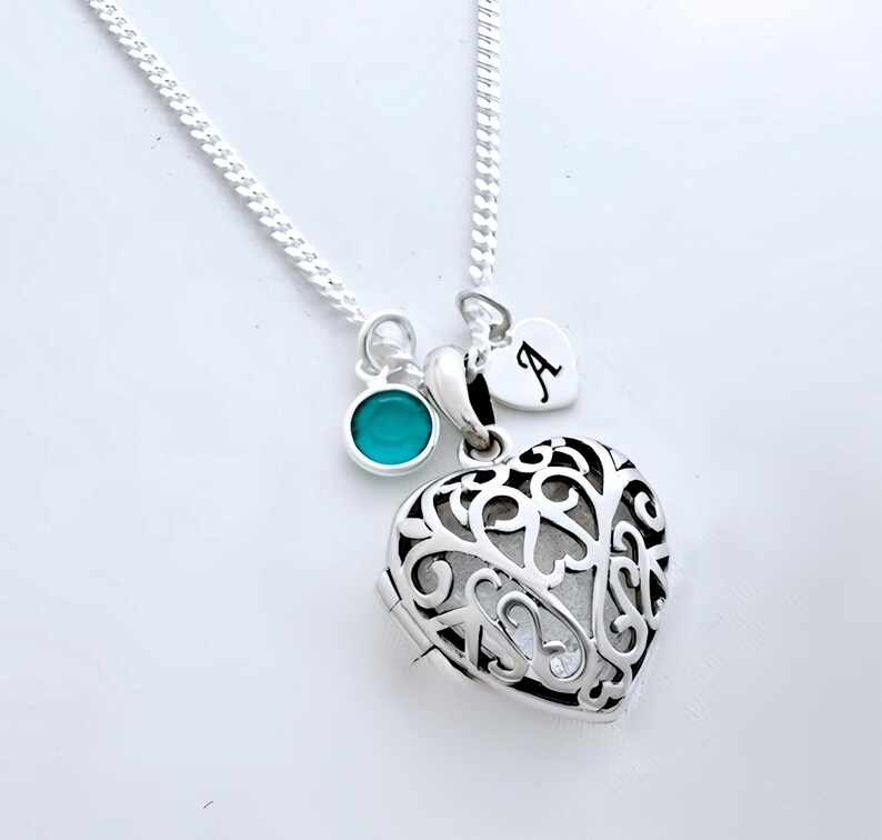 Puede incluir: Un collar de plata con un dije en forma de coraz&oacute;n, un dije turquesa y un peque&ntilde;o dije en forma de coraz&oacute;n con la letra 'A' grabada.