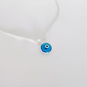 May include: A silver chain necklace with a blue evil eye pendant. The pendant is round and has a white center.