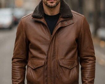 May include: A brown leather jacket featuring a dark brown faux fur collar, a front zipper closure with a snap-button placket, two large front flap pockets with snap buttons, and ribbed knit cuffs and hem, worn over a black shirt and black pants.