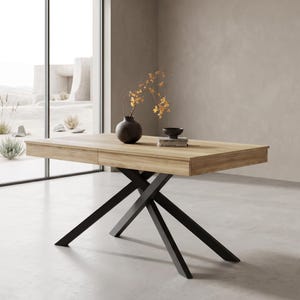 Può includere: Un tavolo da pranzo rettangolare con piano in legno color marrone chiaro e base in metallo nero con gambe incrociate a forma di X. Sul tavolo sono poggiati un vaso rotondo scuro con rami fioriti gialli e una piccola ciotola nera.