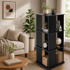 May include: A three-tier black rotating bookshelf with an open square design. The unit features vertical dividers creating multiple storage compartments, currently holding books, a small hourglass, a round clock, and a woven basket.