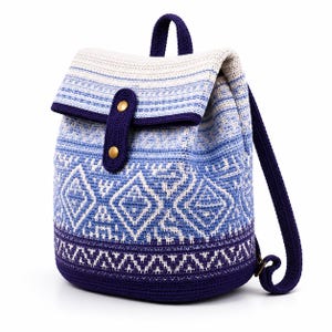 May include: A crochet backpack featuring a gradient of white, light blue, and dark purple yarn. The bag displays a geometric diamond pattern, a top flap with a dark purple strap, and two gold-toned metal snap buttons for secure closure.