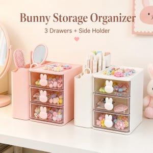 Könnte beinhalten: Zwei Schreibtisch-Organizer, einer in Rosa und einer in Weiß, mit jeweils drei transparenten Schubladen mit weißen, hasenförmigen Griffen und einem Seitenfach. Der Text Bunny Storage Organizer 3 Drawers + Side Holder ist sichtbar.