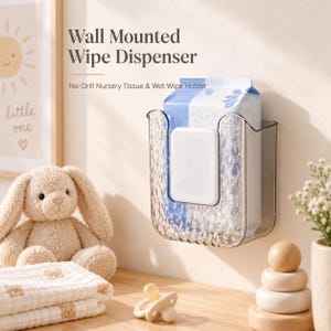 Op de afbeelding: Een doorzichtige, aan de muur gemonteerde doekjesdispenser van kunststof met een getextureerd oppervlak, met daarin een pak vochtige doekjes. De tekst "Wall Mounted Wipe Dispenser" en "No-Drill Nursery Tissue & Wet Wipe Holder" staat erboven.