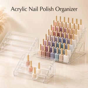 Peut inclure: Un présentoir à vernis à ongles en acrylique transparent avec plusieurs étagères étagées. Le support contient de nombreux flacons de vernis à ongles aux bouchons dorés dans des tons pastel, avec un présentoir vide au premier plan. Texte : Acrylic Nail Polish Organizer.