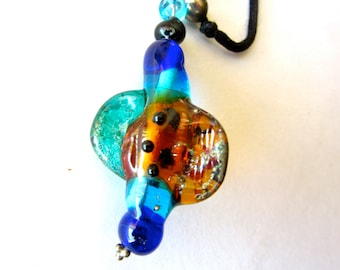 May include: A multi-colored glass pendant with blue, green, orange, and gold accents. The pendant is attached to a black cord.