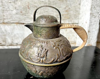 Tetera antigua E. G. Webster, plateada repujada sobre cobre, con asa envuelta en ratán.