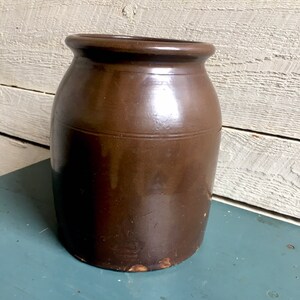 Puede incluir: Un tarro de barro marr&oacute;n esmaltado con una boca ancha y un cuerpo redondeado. El tarro tiene un aspecto r&uacute;stico y vintage y es perfecto para guardar y exhibir objetos.