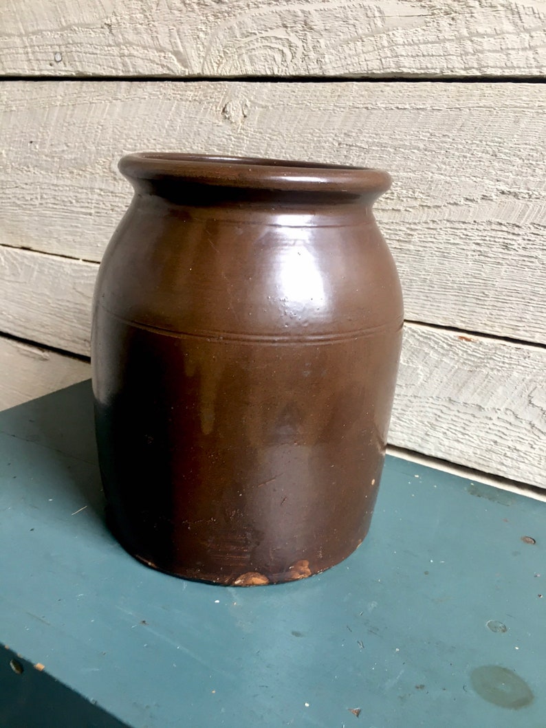 Puede incluir: Un tarro de barro marr&oacute;n esmaltado con una boca ancha y un cuerpo redondeado. El tarro tiene un aspecto r&uacute;stico y vintage y es perfecto para guardar y exhibir objetos.