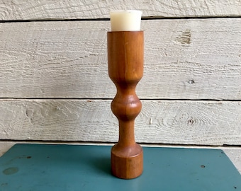 Puede incluir: Un portavelas de madera con un diseño sencillo y moderno de mediados de siglo. El portavelas está hecho de madera natural y tiene una forma redonda y lisa. Es perfecto para agregar un toque de elegancia rústica a cualquier hogar.