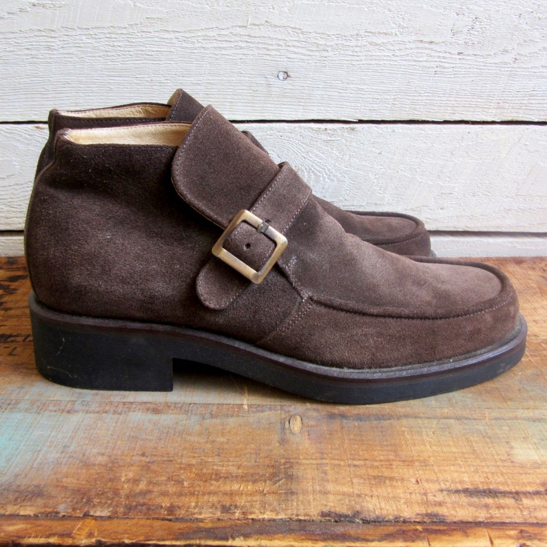 May include: Brown suede ankle boots with a buckle strap and a chunky heel.