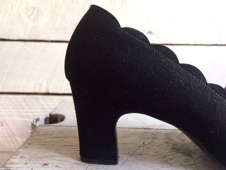 May include: Black suede heeled shoe with a scalloped edge and a chunky heel.