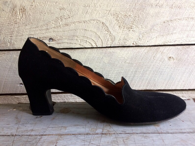 May include: Black suede heeled shoes with a scalloped edge detail.